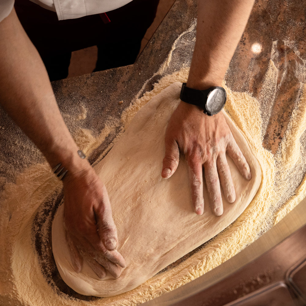 Nahaufnahme einer Person die Pizzateig formt
